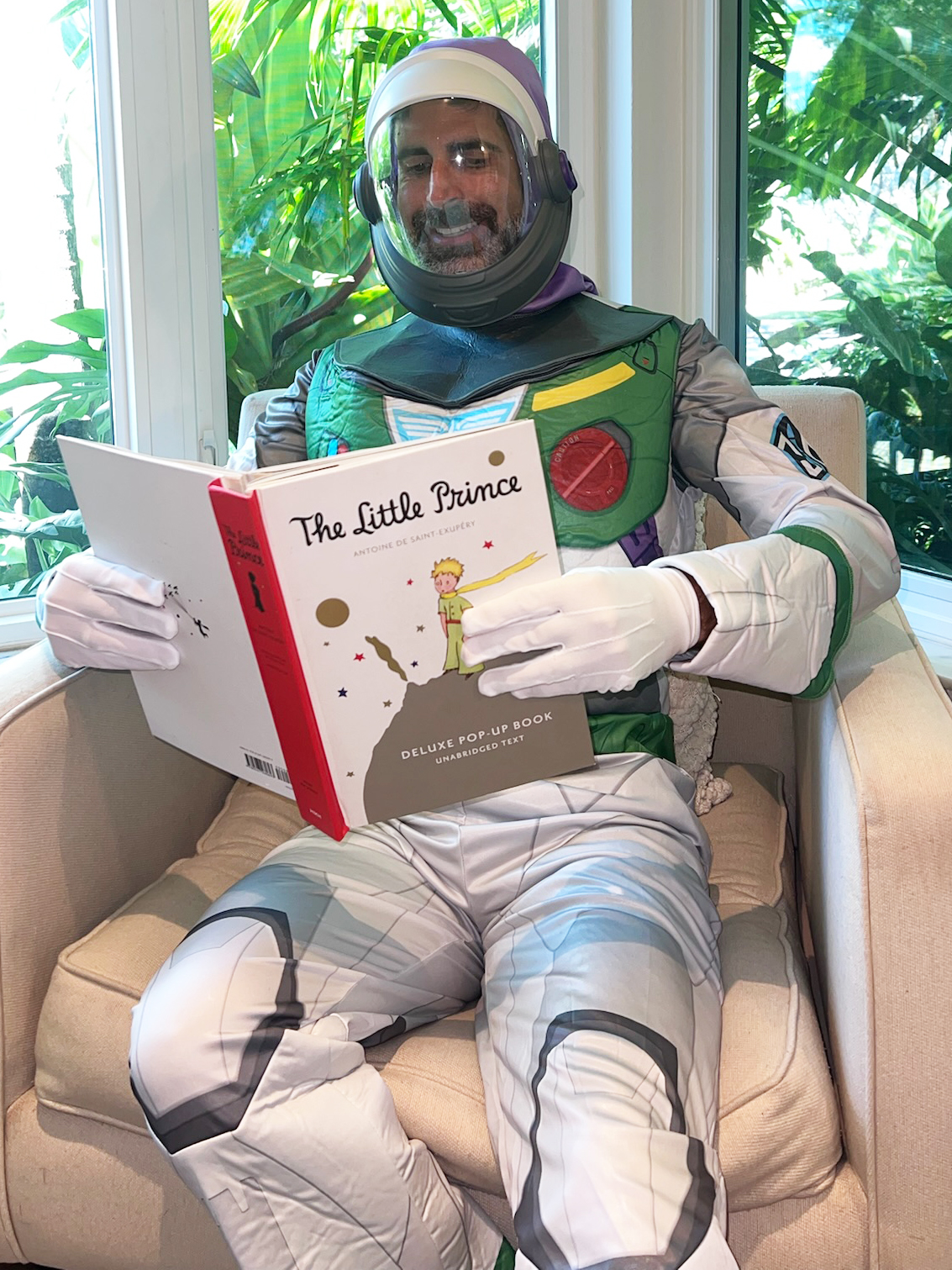 Jorge in a Buzz Lightyear costume sitting and reading The Little Prince