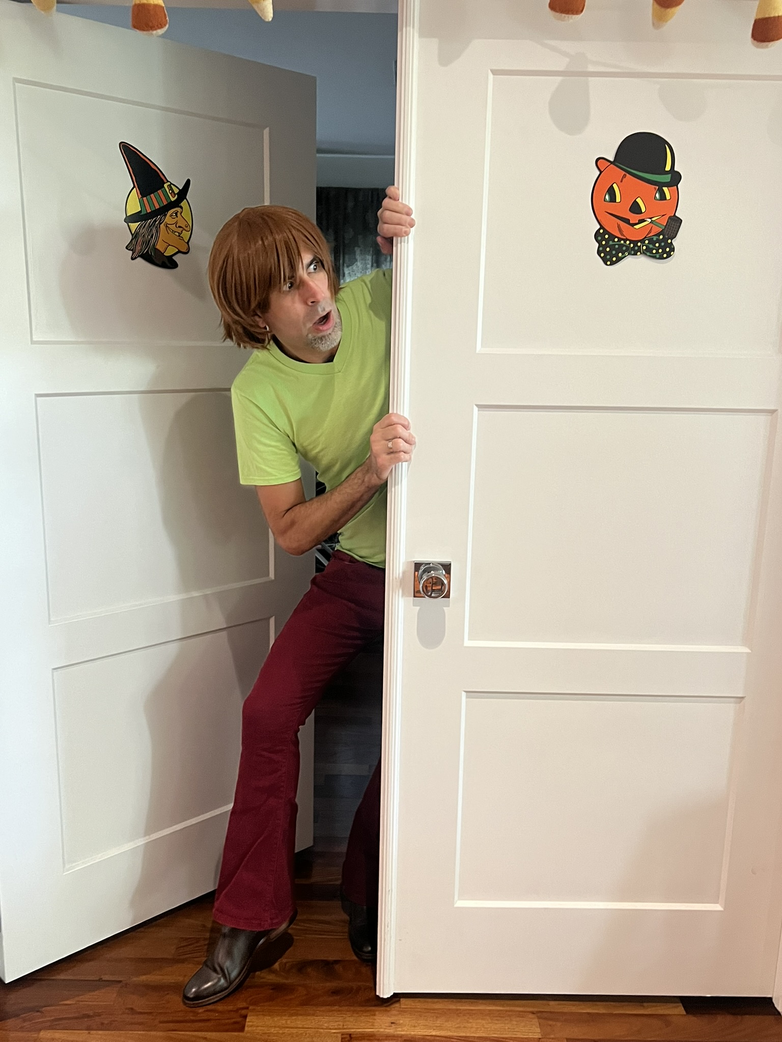 Jorge dressed as Shaggy from Scoby Doo peeking around a door